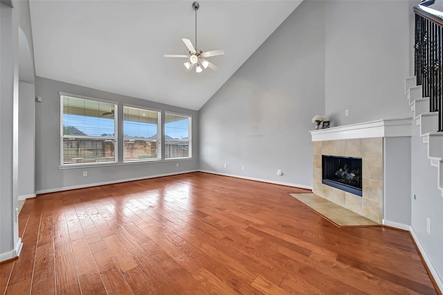 unfurnished living room featuring baseboards, a ceiling fan, a tile fireplace, and wood finished floors