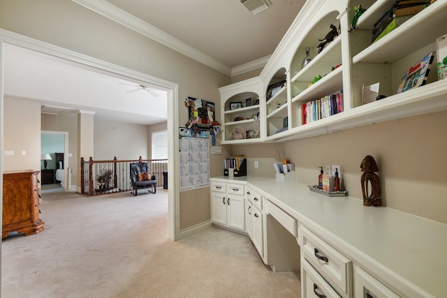 interior space with built in study area, crown molding, open shelves, visible vents, and light colored carpet