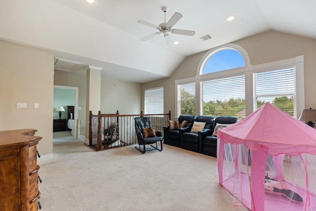 living area featuring visible vents, a ceiling fan, attic access, vaulted ceiling, and light colored carpet