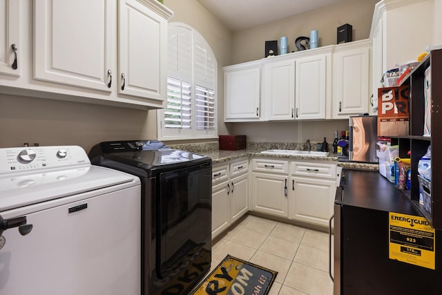 washroom featuring light tile patterned floors, washer and clothes dryer, a sink, and cabinet space