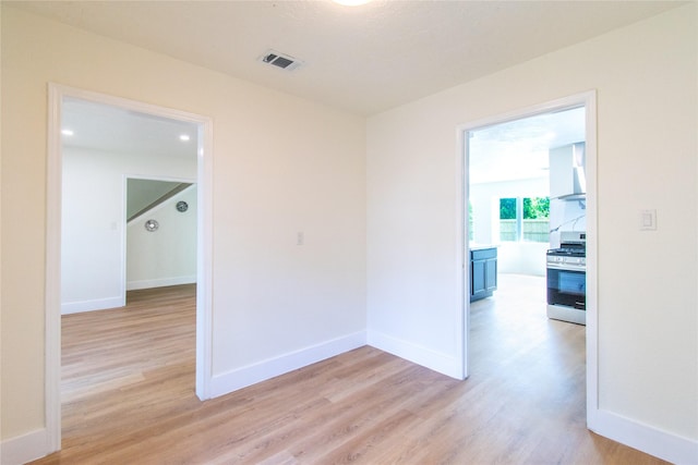 spare room with baseboards, light wood-type flooring, and visible vents