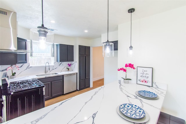 kitchen featuring light wood-type flooring, dishwasher, a sink, light stone counters, and black gas range
