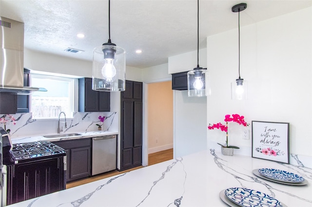 kitchen with stainless steel dishwasher, light stone countertops, a sink, gas stove, and ventilation hood
