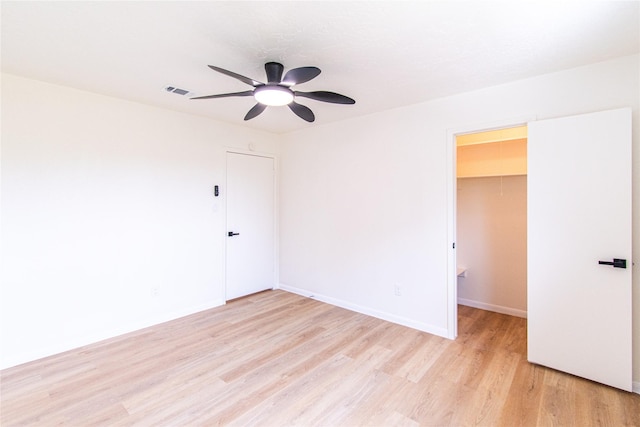 empty room with baseboards, a ceiling fan, light wood-type flooring, and visible vents