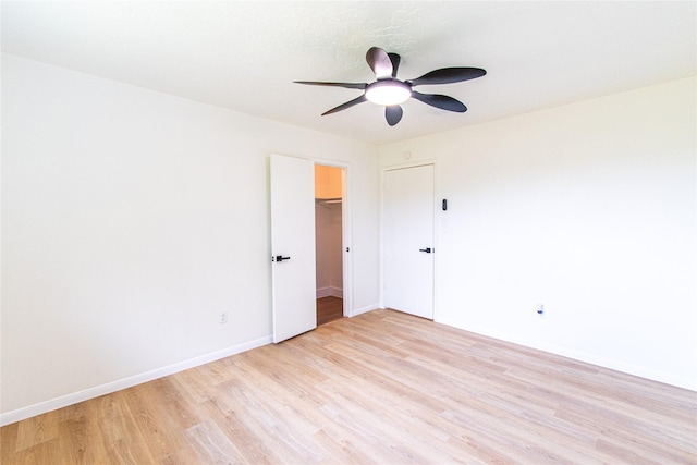 unfurnished bedroom featuring baseboards, light wood finished floors, ceiling fan, and a closet