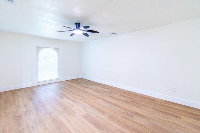 spare room with a ceiling fan, baseboards, visible vents, and light wood-style floors