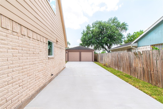 view of side of home with brick siding, fence, an outdoor structure, and a garage