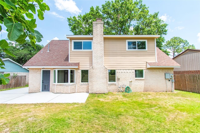 rear view of property with a chimney, a patio area, brick siding, fence, and a yard