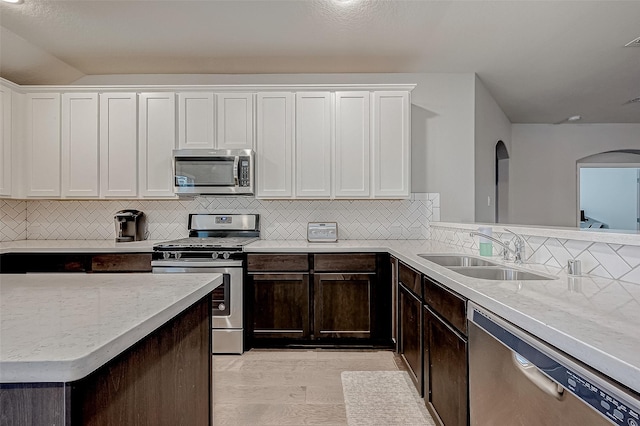 26626 Yukon Straight Dr, Richmond, TX 77406 - kitchen featuring dark brown cabinetry, white cabinetry, appliances with stainless steel finishes, a sink, and backsplash