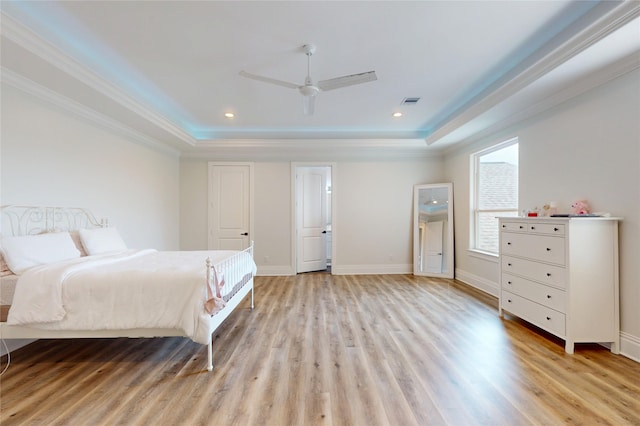 bedroom featuring crown molding, visible vents, a raised ceiling, and light wood-type flooring
