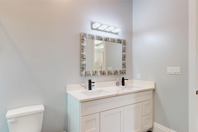 full bath with double vanity, toilet, and a sink