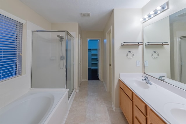 full bath with a sink, visible vents, a spacious closet, and a shower stall