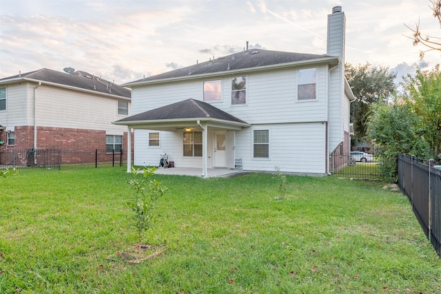 back of house with a patio, a chimney, a fenced backyard, and a lawn