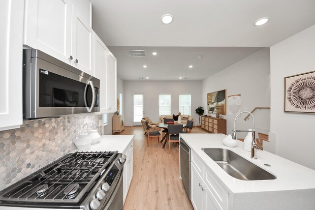 1049 Glenn Ave, Houston, TX 77088 - kitchen with light wood-style floors, white cabinets, visible vents, appliances with stainless steel finishes, and a sink