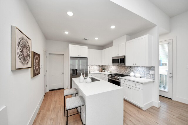 1049 Glenn Ave, Houston, TX 77088 - kitchen with a sink, appliances with stainless steel finishes, an island with sink, white cabinetry, and backsplash