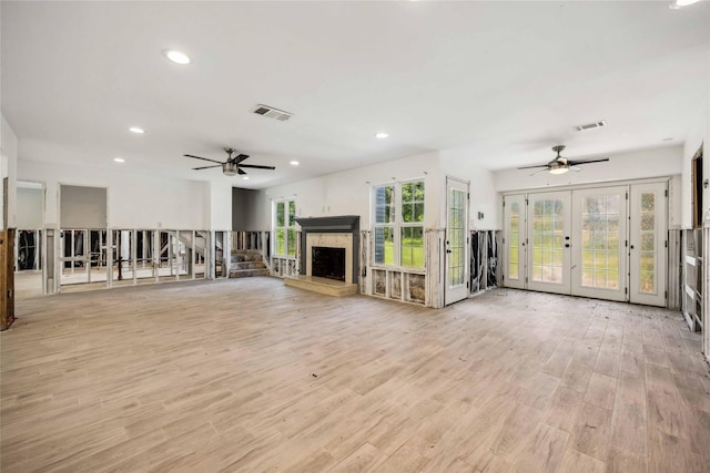 unfurnished living room with ceiling fan, french doors, visible vents, and a fireplace
