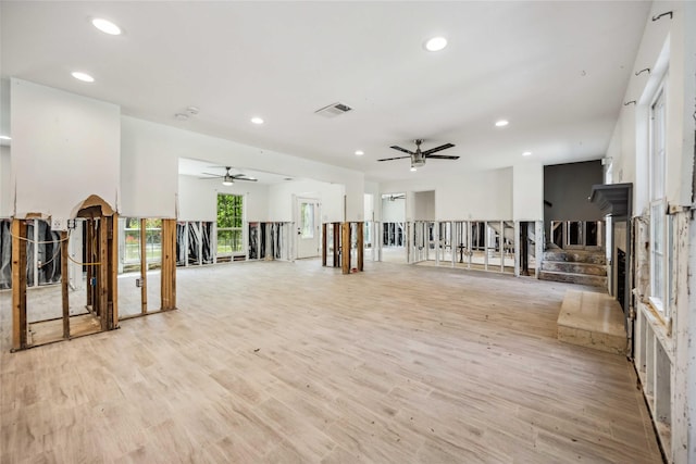 unfurnished living room with stairway, ceiling fan, recessed lighting, and light wood-type flooring