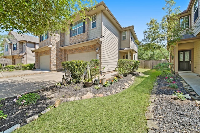 view of side of property featuring a lawn, fence, stone siding, concrete driveway, and an attached garage
