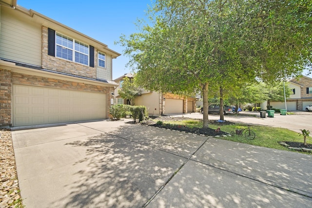 view of front of home with an attached garage, concrete driveway, and stone siding