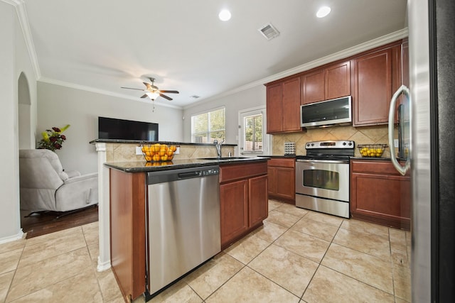 kitchen with visible vents, ornamental molding, open floor plan, a sink, and appliances with stainless steel finishes