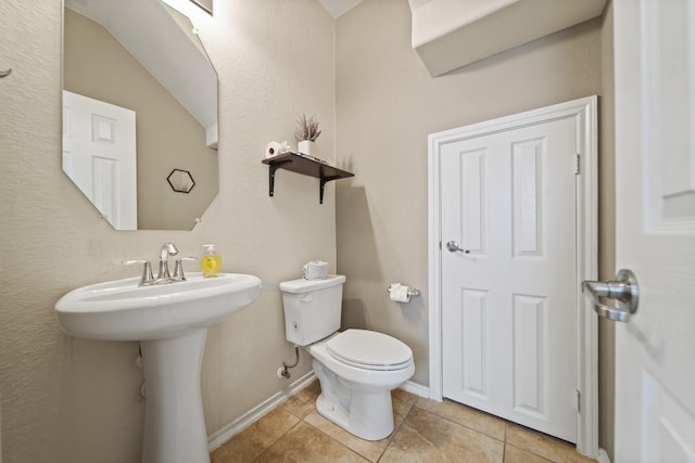 half bathroom with baseboards, tile patterned floors, and toilet
