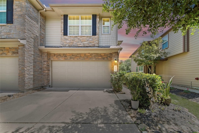 traditional-style house with an attached garage, driveway, and stone siding