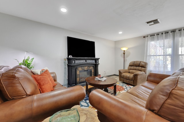 living area with a stone fireplace, visible vents, and recessed lighting