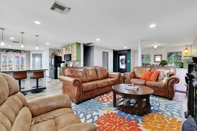 living room with light wood-style flooring, visible vents, recessed lighting, and ornate columns