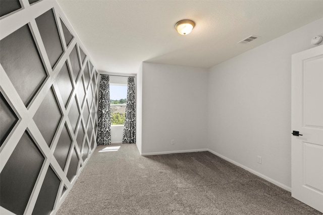 carpeted spare room featuring baseboards and visible vents
