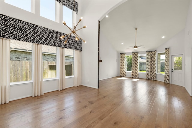interior space with baseboards, high vaulted ceiling, arched walkways, ceiling fan with notable chandelier, and wood finished floors