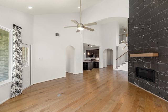 living area featuring light wood-style flooring, arched walkways, a ceiling fan, and visible vents