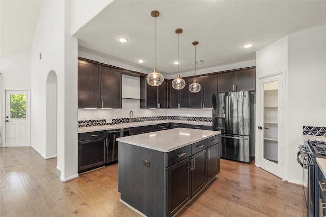 kitchen featuring light wood-style flooring, a center island, light countertops, decorative backsplash, and appliances with stainless steel finishes