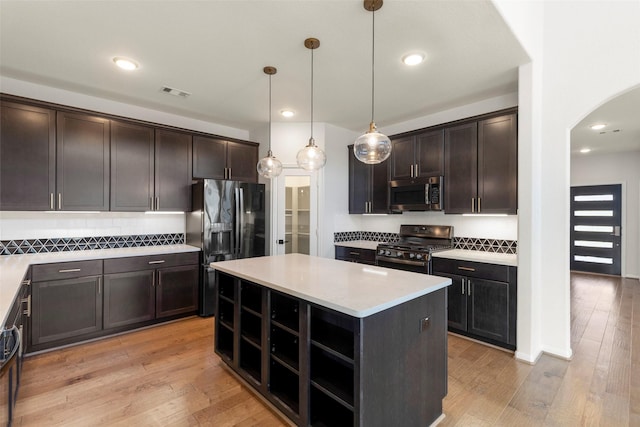 kitchen with arched walkways, light wood-type flooring, visible vents, and stainless steel appliances