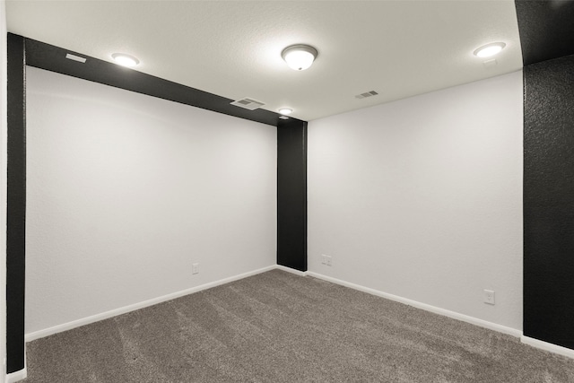 carpeted spare room with visible vents and baseboards