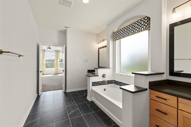 full bathroom featuring visible vents, a bath, vanity, and baseboards