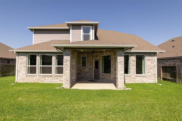 rear view of property featuring a patio area, fence, a lawn, and roof with shingles