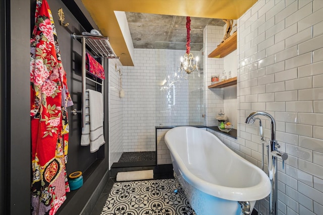 full bathroom with tile patterned flooring, a sink, a freestanding tub, and tile walls