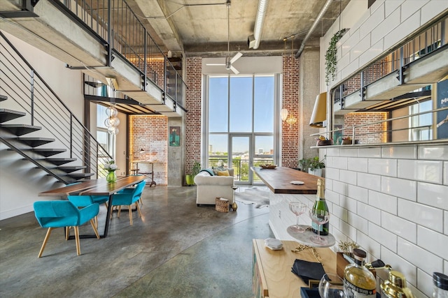 2000 Bagby St Unit 5400, Houston, TX 77002 - dining space featuring a towering ceiling, brick wall, concrete floors, and stairs