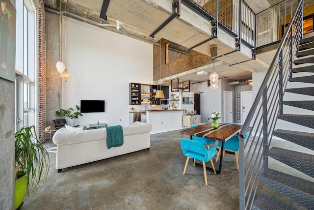 living area featuring concrete floors, stairs, and a towering ceiling