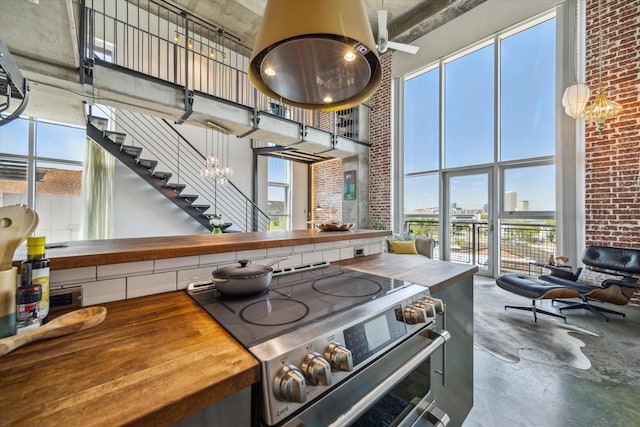 kitchen featuring wood counters, plenty of natural light, stainless steel range with electric stovetop, and a towering ceiling