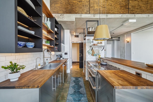 kitchen with decorative backsplash, wooden counters, appliances with stainless steel finishes, open shelves, and concrete floors