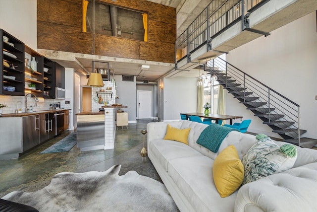 living room with finished concrete floors, stairs, and baseboards