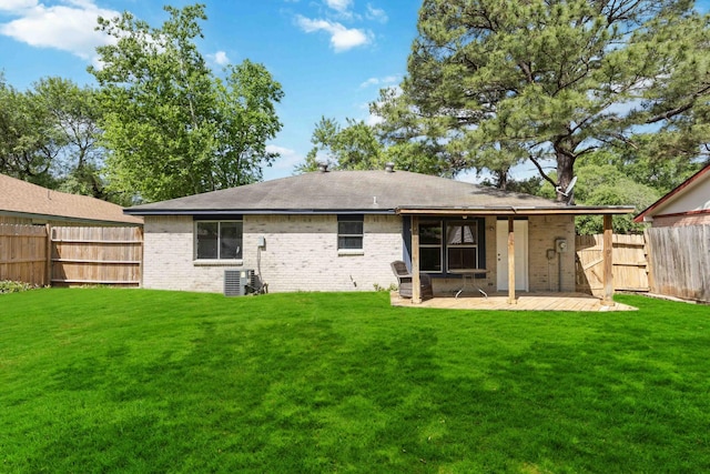 rear view of house featuring brick siding, fence, cooling unit, and a lawn
