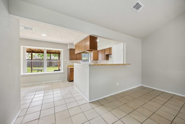 kitchen with brown cabinets, visible vents, light countertops, and light tile patterned flooring