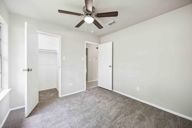 unfurnished bedroom featuring visible vents, baseboards, a closet, a walk in closet, and carpet flooring