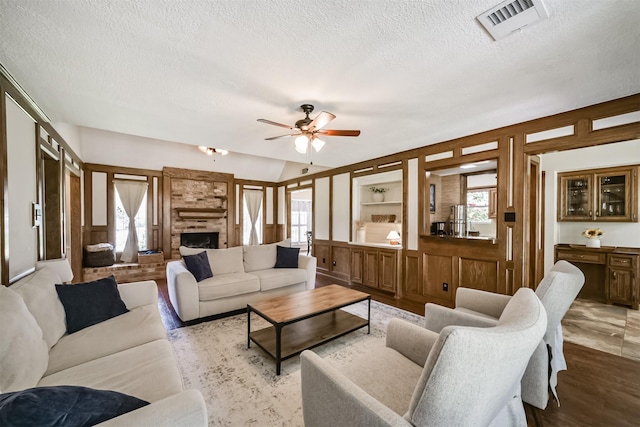 living room featuring a textured ceiling, visible vents, a wealth of natural light, and a brick fireplace