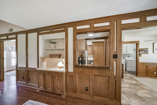 interior space featuring a decorative wall, a wainscoted wall, a textured ceiling, and visible vents