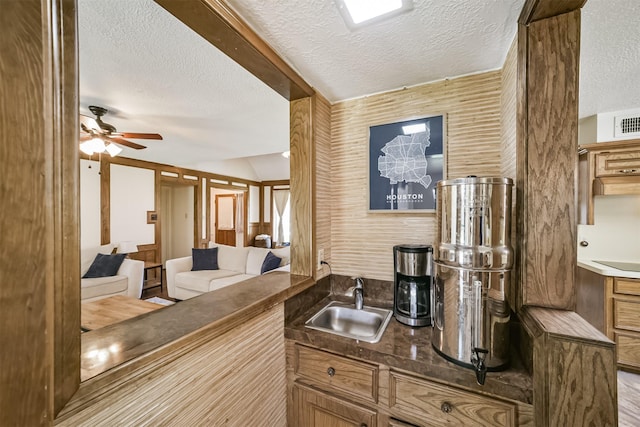 bar featuring black electric stovetop, a ceiling fan, a sink, and a textured ceiling