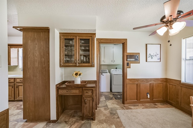 interior space with wainscoting, washing machine and dryer, a textured ceiling, and ceiling fan
