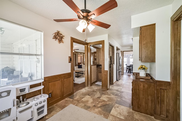 interior space featuring a textured ceiling and wainscoting